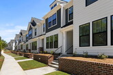 Located in Northside Townes, Spartanburg, SC, this two-story townhome offers 1,380 square feet of thoughtfully designed living space across 3 bedrooms and 5 bathrooms. The main floor (610 sq ft) features an open-concept kitchen and living area. The kitchen is equipped with dark espresso cabinetry, granite countertops, stainless steel appliances, and a large peninsula island with bar seating — ideal for casual dining and entertaining. Light hardwood flooring runs throughout, complementing the bright, neutral color palette. The living room features multiple windows with outdoor views, filling the space with abundant natural light. The upper floor (770 sq ft) houses all three bedrooms, including a spacious primary suite of 220 square feet complete with a ceiling fan, a walk-in closet, and a private en-suite bathroom. Additional bedrooms are well-sized, each outfitted with ceiling fans and convenient access to one of the five bathrooms. Bathrooms are finished with dark vanity cabinetry, white quartz countertops, undermount sinks, and brushed nickel fixtures. Select bathrooms include tub/shower combos. A dedicated closet and two hallways provide ample storage and connectivity throughout this well-appointed home.
