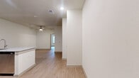 This efficiently designed one-bedroom, one-bathroom unit offers a thoughtfully planned single-floor layout with a clean, modern aesthetic throughout. Light wood-tone flooring flows seamlessly across every room, creating a cohesive and airy feel complemented by crisp white walls and recessed lighting.

The open-concept kitchen is a standout feature, equipped with stainless steel appliances including a refrigerator, electric range, and over-the-range microwave. Rich dark-toned cabinetry pairs with granite countertops, and a peninsula with an integrated sink provides additional prep space and casual seating opportunities, making it the natural hub of the living area. A ceiling fan overhead enhances comfort in the connected living space, which also benefits from natural light filtering in through a window.

The bedroom is a comfortable, well-proportioned retreat featuring a ceiling fan, a window with blinds for natural light and privacy, and direct access to a generously sized walk-in closet outfitted with dual hanging rods and built-in shelving. A second closet provides additional storage flexibility.

The bathroom mirrors the design language of the kitchen, featuring a dark wood vanity with granite countertop, a framed mirror, and wood-tone flooring. A dedicated laundry area rounds out this practical and polished unit.
