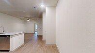 This efficiently designed one-bedroom, one-bathroom unit offers a thoughtfully planned single-floor layout with a clean, modern aesthetic throughout. Light wood-tone flooring flows seamlessly across every room, creating a cohesive and airy feel complemented by crisp white walls and recessed lighting.

The open-concept kitchen is a standout feature, equipped with stainless steel appliances including a refrigerator, electric range, and over-the-range microwave. Rich dark-toned cabinetry pairs with granite countertops, and a peninsula with an integrated sink provides additional prep space and casual seating opportunities, making it the natural hub of the living area. A ceiling fan overhead enhances comfort in the connected living space, which also benefits from natural light filtering in through a window.

The bedroom is a comfortable, well-proportioned retreat featuring a ceiling fan, a window with blinds for natural light and privacy, and direct access to a generously sized walk-in closet outfitted with dual hanging rods and built-in shelving. A second closet provides additional storage flexibility.

The bathroom mirrors the design language of the kitchen, featuring a dark wood vanity with granite countertop, a framed mirror, and wood-tone flooring. A dedicated laundry area rounds out this practical and polished unit.