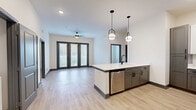 Located at 944 Broadcast Pl in Jacksonville, FL, this well-appointed 2-bedroom, 3-bathroom residence offers a thoughtfully designed single-floor layout with modern finishes throughout. The open-concept living and kitchen area serves as the heart of the home, where light wood-look flooring, recessed lighting, and a ceiling fan create a bright and inviting atmosphere. Large glass doors in the living area allow natural light to pour in and provide access to the outdoors. The kitchen is equipped with stainless steel appliances — including a refrigerator, range, microwave, and dishwasher — complemented by a two-tone cabinet design featuring gray lower cabinets and white upper cabinets, a subway tile backsplash, and a white quartz island with pendant lighting overhead. Both bedrooms feature plush carpeting, generous windows with outdoor views, and dedicated closets, including a well-organized walk-in closet with built-in shelving and hanging rods. The three bathrooms are finished with gray cabinetry, white quartz countertops, matte black fixtures, and wood-look flooring. The primary bathroom includes a soaking tub with tiled surround, while another features a dual-sink vanity with a steel-framed glass door as a standout design element.