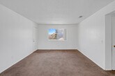 Located at 501 E Virginia Way in Barstow, California, this single-floor residence offers a practical and well-organized layout comprising two bedrooms, two bathrooms, a kitchen, a hallway, and two closets. The living area features warm neutral carpeting and a textured ceiling, with an open sightline toward the kitchen. A ceiling fan with light fixture adds comfort to the dining and living space, which connects to a sliding glass door that brings in natural light and outdoor views. The kitchen is equipped with warm wood-toned cabinetry lining both sides of the galley-style layout, granite-style countertops, a double basin sink, a dishwasher, and durable hardwood-style flooring. The primary bedroom is a well-proportioned room with plush carpeting, a large window offering neighborhood views, and direct access to a closet. The second bedroom also features carpet flooring, neutral walls, and a textured ceiling. Both bathrooms are finished with tile flooring, granite-style vanity countertops, and white cabinetry. One bathroom includes a full tub-shower combination. Throughout, the residence maintains a clean, neutral palette that provides a versatile canvas for personalization.