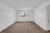 Located at 501 E Virginia Way in Barstow, California, this single-floor residence offers a practical and well-organized layout comprising two bedrooms, two bathrooms, a kitchen, a hallway, and two closets. The living area features warm neutral carpeting and a textured ceiling, with an open sightline toward the kitchen. A ceiling fan with light fixture adds comfort to the dining and living space, which connects to a sliding glass door that brings in natural light and outdoor views. The kitchen is equipped with warm wood-toned cabinetry lining both sides of the galley-style layout, granite-style countertops, a double basin sink, a dishwasher, and durable hardwood-style flooring. The primary bedroom is a well-proportioned room with plush carpeting, a large window offering neighborhood views, and direct access to a closet. The second bedroom also features carpet flooring, neutral walls, and a textured ceiling. Both bathrooms are finished with tile flooring, granite-style vanity countertops, and white cabinetry. One bathroom includes a full tub-shower combination. Throughout, the residence maintains a clean, neutral palette that provides a versatile canvas for personalization.