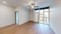 Located at 18545 Hilliard Blvd in Rocky River, Ohio, this thoughtfully designed one-bedroom, one-bathroom residence offers a clean, modern aesthetic across a well-appointed single floor. The open-concept kitchen and living area serves as the heart of the home, featuring warm light wood flooring, crisp white cabinetry, a subway tile backsplash, stainless steel appliances, and a striking oversized island topped with a veined quartz countertop. Globe pendant lights add a stylish finishing touch overhead. The living area extends naturally toward a full-glass balcony door, flooding the space with natural light and providing access to an outdoor balcony with open views of the surrounding landscape. The generously sized bedroom is finished with plush carpeting, a ceiling fan, and floor-to-ceiling windows that frame scenic outdoor views. It connects directly to a dedicated laundry room equipped with a stacked washer and dryer unit and built-in shelving. The bathroom showcases a dual-sink vanity with wood-toned cabinetry and quartz counters, a large mirror with modern lighting, and a glass-enclosed shower. Wood-look plank flooring ties the bathroom together with the rest of the home's cohesive, contemporary design.