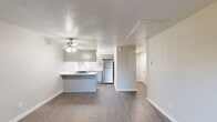 This single-floor residence offers a thoughtfully designed layout that balances comfort and functionality. The open-concept living and kitchen area serves as the heart of the unit, featuring durable wood-look flooring, a textured ceiling with a ceiling fan, and a sliding glass door that fills the space with natural light and provides direct access to the outdoors. The kitchen is efficiently arranged in a galley style, equipped with gray shaker-style cabinetry, white countertops, stainless steel appliances including a refrigerator and electric range, and a built-in dishwasher. A peninsula counter connects the kitchen to the living area, creating a convenient pass-through that enhances the open feel of the space. The bedroom is carpeted for warmth and comfort, outfitted with two generously sized closets with sliding and hinged doors, a ceiling fan, and a window with blinds that overlooks greenery outdoors. The full bathroom features wood-look flooring, a vanity with storage, and a full-size tub and shower combination with grab bar support. A dedicated hallway connects the main living area to the private sleeping and bathroom quarters, providing a clear and practical separation of spaces throughout the unit.