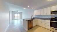 This single-floor residence offers two bedrooms and two full bathrooms within a thoughtfully designed layout. A welcoming entry hallway with light tile flooring leads into the main living area, where the open-concept kitchen and living room create a cohesive, functional space. The kitchen is well-equipped with white shaker-style cabinetry, granite countertops, stainless steel appliances including a range, microwave, dishwasher, and refrigerator, and a peninsula with a sink that provides additional workspace and casual seating opportunities. Recessed lighting and a ceiling fan enhance the living area, which features access to an outdoor balcony offering exterior views.

Both bedrooms are comfortably sized, with ceiling fans, ample natural light from large windows, and soft carpet flooring. The two bathrooms mirror each other in design, featuring white cabinetry, granite-topped vanities with brushed nickel hardware, and tile flooring. One bathroom includes a full bathtub-shower combination, while the other offers a more compact configuration. A dedicated in-unit laundry room with a full-size washer and dryer and overhead shelving adds everyday convenience. The overall aesthetic is clean and neutral throughout.
