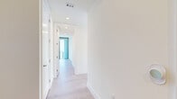 Located in the heart of downtown Austin, TX, this thoughtfully designed one-bedroom, two-bathroom residence offers a sophisticated urban living experience. Light wide-plank hardwood flooring runs throughout the main living areas, complemented by crisp white walls and recessed lighting that create a clean, contemporary aesthetic.

The open-concept kitchen and living area is anchored by a well-appointed galley-style kitchen featuring stainless steel appliances, including a gas range with hood, built-in microwave, and oven, all set against white cabinetry and a subway tile backsplash with bright white countertops. The layout flows seamlessly into the living area, where dramatic floor-to-ceiling windows and sliding glass doors open to a private balcony showcasing sweeping views of the Austin skyline.

The spacious bedroom continues the floor-to-ceiling window theme, flooding the room with natural light and framing panoramic city vistas. A generously sized walk-in closet with built-in shelving and hanging rods provides ample storage. Both bathrooms are elegantly finished with marble-style tile, a soaking tub with shower combination, and white vanities with brushed hardware. A dedicated in-unit laundry room with a front-loading Whirlpool washer completes this well-appointed residence.