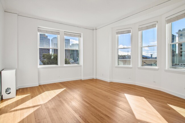 Spacious room with wood-like flooring and a large window offering natural light - 645 Stockton Street