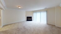Located in Bethesda, MD, this two-floor residence offers a well-organized layout with comfortable living spaces spread across both levels. The main living area is generously sized, featuring plush wall-to-wall carpeting, crown molding, and a classic fireplace as a focal point, flanked by floor-to-ceiling vertical blinds that allow abundant natural light to pour in. The galley-style kitchen is efficiently designed with rich wood cabinetry, dark granite-style countertops, tile backsplash, light tile flooring, and a full suite of black appliances including a range, refrigerator, microwave, and dishwasher. The bedrooms are spacious and carpeted, each benefiting from windows that frame views of surrounding greenery, lending a serene, natural ambiance throughout. The bathrooms are finished with warm beige tile work — one featuring a tub-shower combination with decorative tile accents, and another offering a glass-enclosed walk-in shower with matching tile detailing and tile flooring. Additional rooms throughout the home provide flexible space, all finished with neutral tones and clean white trim. The overall aesthetic is understated and move-in ready, offering a calm, functional environment in a sought-after Bethesda location.