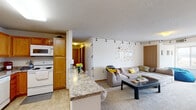 Located at 2601 University Ave SE in Minneapolis, this single-floor unit offers a practical and functional layout well-suited for everyday living. The open-concept design connects the kitchen and living area seamlessly, creating a welcoming communal space. The kitchen is equipped with warm honey-toned wood cabinetry, granite-style countertops, a full suite of white appliances including a refrigerator, electric range, dishwasher, and over-the-range microwave, as well as a double sink. Light tile flooring ties the space together efficiently.

The living area features plush carpeting and flows naturally from the kitchen peninsula, offering generous room for seating and relaxation. A wide window at the far end of the living space allows natural light to fill the room, with views of the surrounding neighborhood.

The unit includes multiple carpeted bedrooms, each with windows providing natural light and ample wall space. The bedrooms offer flexibility for both sleeping and study arrangements. Two bathrooms serve the unit, each finished with tile flooring, wood-toned cabinetry, and clean, simple fixtures. Additional storage is available via walk-in closet space visible from one of the secondary kitchenette areas. Textured ceilings are consistent throughout the unit.