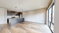 Located at 1 Chestnut St in Norwalk, CT, this modern one-bedroom, one-bathroom unit offers a well-designed layout with contemporary finishes throughout. Wood-style plank flooring flows seamlessly across the entire space, lending warmth and cohesion to every room.

The open-concept kitchen and living area serves as the heart of the unit. The kitchen is equipped with dark flat-front cabinetry reaching to the ceiling, stainless steel appliances including a range, microwave, and refrigerator, a white subway tile backsplash, and a large island with a quartz countertop, undermount sink, and industrial-style faucet. Pendant lighting adds a refined touch overhead. Sleek sliding panel doors offer flexible division between spaces.

The bedroom is a well-proportioned retreat featuring large floor-to-ceiling windows that flood the room with natural light and provide views of the surrounding Norwalk cityscape. A wall-mounted split HVAC unit ensures year-round climate control. The bedroom connects directly to a dedicated closet outfitted with wire shelving and hanging rods for organized storage.

The bathroom is finished with large-format tile flooring, a dark wood vanity with a double sink and quartz countertop, and a separate walk-in shower enclosed by a glass door with white subway tile surround, delivering a clean, spa-like aesthetic.