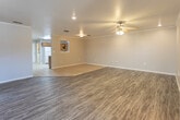 This single-story home offers a thoughtfully laid-out floor plan with a variety of functional spaces. The expansive living area is finished with durable wood-look flooring and transitions seamlessly into a tiled entryway, complemented by crown molding, recessed lighting, and a ceiling fan that add to the room's polished feel. A front entry door with an arched window allows natural light to filter into the main living space.

The kitchen is well-equipped, featuring warm oak cabinetry that extends from floor to ceiling, white countertops, a double-basin sink, a white electric range with overhead ventilation, and a dishwasher. Light tile flooring and a flush-mount ceiling fixture keep the space bright and practical. A pass-through window detail adds an open, connected feel to the kitchen layout.

The bedrooms are carpeted for comfort and include ceiling fans with light fixtures. One bedroom features a walk-in closet accessible through a secondary door, along with a window dressed with blinds that brings in natural light.

The bathrooms are consistent in their finishes, each featuring oak vanity cabinetry, white countertops, large mirrors, tile flooring, and a tub-shower combination. Additional overhead cabinetry provides ample storage. The overall aesthetic throughout the home is clean, neutral, and functional.