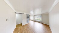Located at 5965 Evergreen Road in Dearborn Heights, MI, this 2-bedroom, 1-bathroom unit offers a clean, modern aesthetic across its single-floor layout. Light wood laminate flooring runs throughout, creating a bright and cohesive feel in every room.

The living room is a comfortable, open space filled with natural light from a large window dressed with vertical blinds, offering views of the surrounding neighborhood. A standout design element is the sliding barn door with a reclaimed wood accent wall, adding a rustic-modern touch to the living area.

The kitchen is efficiently laid out with white cabinetry, dark granite countertops, and a full suite of stainless steel appliances including a refrigerator, gas range, and over-the-range microwave. Light wood flooring continues seamlessly into this space.

The primary bedroom is generously sized with a double-door closet and direct access to the hallway. The second bedroom features a window with vertical blinds and a wall-mounted air conditioning unit, providing independent climate control. Both bedrooms maintain the same light, neutral palette found throughout the unit.

The bathroom is neatly finished with large-format grey stone-look tile on both the floors and walls, a soaking tub with a handheld showerhead, a white vanity, and a dark granite countertop, tying together the unit's consistent design language.