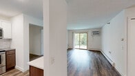 Located at 2730 Hazelwood St in Maplewood, MN, this 2-bedroom, 2-bathroom unit delivers a well-organized, single-floor layout with a thoughtful blend of modern updates and practical design. The open living room features rich hardwood-style flooring, a wall-mounted AC unit, and sliding glass doors that lead to a private balcony overlooking lush greenery, allowing natural light to fill the space. The kitchen is well-appointed with stainless steel appliances — including a refrigerator, range, microwave, and dishwasher — complemented by white upper cabinetry, warm wood lower cabinets, gray countertops, and a classic subway tile backsplash with recessed lighting overhead. Both bedrooms are carpeted and include ceiling fans and wall AC units for year-round comfort. The primary bedroom features a closet and direct access to a sleekly updated en-suite bathroom, while the second bedroom also includes a closet and natural window light. The bathrooms are finished with large-format gray tile, warm wood vanities, white countertops, and modern fixtures. A hallway connects the rooms seamlessly, with durable hardwood-style flooring carrying throughout the main living areas. This unit combines contemporary finishes with comfortable, functional living.
