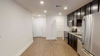 This single-floor residence in Castle Shannon, PA offers a clean, modern aesthetic throughout its thoughtfully designed layout. The open living and kitchen area is anchored by warm-toned luxury vinyl plank flooring and illuminated by recessed lighting, creating a bright and welcoming atmosphere. The kitchen is a standout feature, equipped with dark espresso cabinetry, light granite countertops, and a full suite of stainless steel appliances including a refrigerator, electric range, microwave, and dishwasher. A walk-in pantry with wire shelving provides generous storage directly off the kitchen. The living area offers ample room to arrange furniture comfortably, with easy access to additional spaces via a central hallway. The bathroom is finished with a classic black-and-white mosaic tile floor, a dark vanity with a white countertop, and a full tub-shower combination. The bedroom features plush carpeting, a large window fitted with blinds that allows natural light while maintaining privacy, and a ceiling vent for climate control. A separate living area with dark hardwood-style flooring and a sliding door with vertical blinds rounds out the space, offering versatility and additional natural light.