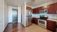 Located on the 11th floor at 10 Commerce Ave SW in the heart of downtown Grand Rapids, Michigan, this 2-bedroom, 2-bathroom residence offers a well-designed layout across a single level. The open-concept living area is anchored by hardwood-style flooring and large windows that frame striking panoramic views of the Grand Rapids skyline, flooding the space with abundant natural light.

The kitchen is equipped with rich mahogany-toned cabinetry, granite countertops, and a full suite of stainless steel appliances including a refrigerator, electric range, built-in microwave, and dishwasher. Track lighting overhead adds a modern, functional touch.

The primary bedroom features hardwood-style flooring and expansive windows showcasing the downtown cityscape, providing a bright and airy atmosphere. The second bedroom is finished with plush carpeting and its own window with skyline views, offering a comfortable and quiet retreat. A dedicated closet provides additional storage convenience.

Both bathrooms are finished with tile flooring and dark vanity cabinetry topped with granite countertops. One bathroom includes a walk-in glass shower, while the other features a full soaking tub with floor-to-ceiling tile surround and chrome fixtures throughout.

This residence combines contemporary urban finishes with a coveted downtown Grand Rapids location.