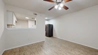 This well-designed one-bedroom, one-bathroom unit offers a practical and comfortable single-floor layout with consistent wood-look flooring flowing throughout every room, creating a cohesive and easy-to-maintain living environment. The living area is bright and open, featuring a ceiling fan with light fixture and a pass-through window connecting to the kitchen, enhancing the sense of openness between spaces. A full-size black refrigerator anchors the kitchen transition area, which is a standout feature of the unit. The kitchen itself is thoughtfully updated with white shaker-style cabinetry, granite countertops, a mosaic tile backsplash in neutral tones, and a full suite of stainless steel appliances including an electric range, over-the-range microwave, and dishwasher. Recessed lighting illuminates the kitchen efficiently. The bedroom is a comfortable, well-proportioned retreat with its own ceiling fan, a window fitted with blinds for natural light and privacy, and clean white walls. The hallway provides a functional transition between rooms, leading to the full bathroom, which includes a tub/shower combination with white tile surround, a toilet, a vanity with white cabinetry, and wood-look flooring that maintains the unit's consistent aesthetic throughout.