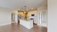 Located at 1550 Kenny Rd in Columbus, Ohio, this single-floor home offers a thoughtfully designed layout with high-quality finishes throughout. The kitchen serves as the heart of the home, featuring crisp white shaker cabinetry, granite countertops, a large center island with an undermount sink, and a decorative arabesque tile backsplash. Stainless steel appliances, including a French door refrigerator, microwave, and range, complement the space, while two elegant pendant lights with brass accents add warmth and character overhead. Hardwood flooring runs throughout the main living and kitchen areas, flowing into a well-lit hallway that connects the home's rooms with ease. The bedrooms are finished with plush carpet and feature windows with blinds that allow for ample natural light. The bathroom is a standout, showcasing bold navy subway tile in the walk-in shower with black-framed glass doors, a granite-topped vanity, intricate geometric patterned floor tile, and gold industrial-style sconce lighting. A dedicated in-unit laundry room houses a full-size washer and dryer alongside the home's mechanical systems. Clean neutral wall tones and white panel doors with black hardware unify the home's modern yet timeless aesthetic throughout.