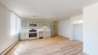 Located at 2424 N Clark St in Chicago's vibrant Lincoln Park neighborhood, this updated single-floor unit offers a clean, modern aesthetic throughout. Light-toned hardwood flooring runs continuously across the open layout, creating a bright and cohesive feel.

The kitchen is a standout feature, outfitted with gray shaker-style cabinetry extending to the ceiling for ample storage, a decorative subway tile backsplash with a mosaic accent border, light quartz countertops, and a full suite of stainless steel appliances including a gas range, microwave, dishwasher, and refrigerator. Track lighting illuminates the space effectively.

The living area is generously sized and bathed in natural light from multiple windows fitted with vertical blinds. A baseboard heating system and wall-mounted air conditioning unit provide year-round climate control. An open closet off the living space offers convenient built-in storage.

The bathroom is thoughtfully renovated, featuring floor-to-ceiling white subway tile surrounding the tub-shower combination, a gray vanity with a white basin, brushed gold fixtures, and stone-look tile flooring. A mirrored medicine cabinet adds both storage and function.

A well-proportioned hallway connects the living spaces to the bathroom and entry, completing this efficiently designed and move-in ready unit in one of Chicago's most sought-after neighborhoods.