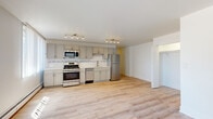 Located at 2424 N Clark St in Chicago's vibrant Lincoln Park neighborhood, this updated single-floor unit offers a clean, modern aesthetic throughout. Light-toned hardwood flooring runs continuously across the open layout, creating a bright and cohesive feel.

The kitchen is a standout feature, outfitted with gray shaker-style cabinetry extending to the ceiling for ample storage, a decorative subway tile backsplash with a mosaic accent border, light quartz countertops, and a full suite of stainless steel appliances including a gas range, microwave, dishwasher, and refrigerator. Track lighting illuminates the space effectively.

The living area is generously sized and bathed in natural light from multiple windows fitted with vertical blinds. A baseboard heating system and wall-mounted air conditioning unit provide year-round climate control. An open closet off the living space offers convenient built-in storage.

The bathroom is thoughtfully renovated, featuring floor-to-ceiling white subway tile surrounding the tub-shower combination, a gray vanity with a white basin, brushed gold fixtures, and stone-look tile flooring. A mirrored medicine cabinet adds both storage and function.

A well-proportioned hallway connects the living spaces to the bathroom and entry, completing this efficiently designed and move-in ready unit in one of Chicago's most sought-after neighborhoods.