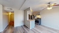 This single-story space is designed with a practical, open layout connecting the living area to the kitchen. The kitchen is well-appointed with gray cabinetry, a mosaic tile backsplash, granite-style countertops, stainless steel appliances including a gas range and refrigerator, and a peninsula with breakfast bar seating that opens to the living space. Wood-look flooring runs consistently throughout the unit, lending a cohesive, modern feel. A ceiling fan is installed in the living area, and a hallway leads to the private rooms.

The bedrooms are comfortable and simply styled, each featuring wood-look flooring, neutral wall tones, ceiling fans with light fixtures, and windows fitted with blinds that allow natural light while maintaining privacy. The textured ceilings are a consistent architectural detail found throughout the space.

Two bathrooms serve the unit. One features a full soaking tub and shower combination with a single-sink vanity with granite-style countertop. The second bathroom includes a walk-in tile shower with floor-to-ceiling tile surround, a toilet, and a matching vanity. Both bathrooms continue the wood-look flooring found throughout the rest of the space, maintaining a unified aesthetic.