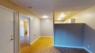This single-floor unit offers a practical and comfortable layout designed for everyday living. The living and dining areas are connected by an open flow, distinguished by warm honey-toned laminate flooring that transitions seamlessly throughout the main spaces. A half-wall partition with a blue accent separates the living area from the kitchen, creating a sense of definition while maintaining an open feel. Flush-mount ceiling lights provide consistent illumination, and textured popcorn ceilings add a classic character to the space.

The kitchen is well-equipped with stainless steel appliances, including a refrigerator, electric range, over-the-range microwave, and dishwasher. White cabinetry with dark granite-style countertops lines the walls, offering ample storage and prep space, all complemented by the same light laminate flooring.

The bedroom is a generously sized, quiet retreat featuring a window that allows natural light to filter in, with views to the outdoors. Rich, dark wood-toned laminate flooring grounds the room, and a walk-in closet provides excellent storage. The full bathroom includes a single-sink vanity with white cabinetry, a large mirror with overhead lighting, and a shower-tub combination, finished in a clean, neutral palette.