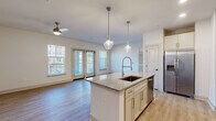 Located at 2415 Robin Lark Dr in Winston-Salem, NC, this 2-bedroom, 2-bathroom residence offers a thoughtfully designed single-floor layout with modern finishes throughout. The open-concept kitchen and living area serves as the heart of the home, centered around a granite-topped island with an undermount sink and pendant lighting. White cabinetry, a subway tile backsplash, stainless steel appliances, and light hardwood-style flooring complete the kitchen's clean, contemporary aesthetic. The living area flows seamlessly from the kitchen and features a ceiling fan, large windows, and French doors that invite abundant natural light and provide access to an outdoor balcony area. The primary bedroom is generously sized, with a ceiling fan, closet access, and a dedicated en-suite bathroom. The second bedroom is bright and airy, benefiting from multiple windows that frame outdoor views and fill the room with sunlight. Both bathrooms are finished with granite countertops and white cabinetry; one features a soaking tub with marble-style tile surround and a built-in niche, paired with brushed gold hardware. Two closets and two entrance points add to the practical functionality of this well-organized floor plan, making this residence both comfortable and efficient.
