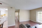 This single-floor residence offers a practical and comfortable layout with two bedrooms and two bathrooms. Rich hardwood flooring flows consistently throughout the main living areas, creating a warm and cohesive aesthetic against the neutral beige walls and white trim.

The living room is an inviting space anchored by a set of French doors that flood the room with natural light while providing access to the outdoors. Adjacent to the living area, the dining room features a ceiling fan and offers a cozy setting for meals, with easy access to the kitchen nearby.

The primary bedroom is a well-sized retreat complete with a large closet featuring bifold doors and a connected bathroom equipped with a wide white vanity, ample cabinet storage, and well-lit mirrors. The second bedroom also benefits from hardwood floors and a window that brings in natural light.

The second bathroom includes a vanity with under-sink storage, open shelving, and tile flooring. Textured ceilings are present throughout much of the unit, adding a classic residential character. The overall design prioritizes functionality and comfort, with a neutral color palette that provides a versatile backdrop for a variety of décor styles.