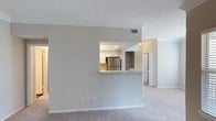 Located at 300 Woodway Bluff Cir in Cary, NC, this single-floor residence offers a well-planned layout with a clean, neutral palette throughout. The open living area is finished with plush wall-to-wall carpeting and crown molding, and connects seamlessly to the kitchen via a pass-through peninsula with a granite-style countertop. The kitchen is efficiently designed with wood-look vinyl flooring, white shaker-style cabinetry, light stone countertops, and a full suite of stainless steel appliances including a GE refrigerator, range, and built-in microwave. Bedrooms are generously sized, each featuring soft carpeting, crown molding, ceiling fans with light fixtures, and windows that bring in natural light with views of surrounding greenery. The primary bedroom includes direct access to an en-suite bathroom. Bathrooms are finished with white vanity cabinetry, wide mirrors, and multi-bulb vanity lighting. One bathroom features a full tub-shower combination with tile surround and wood-look flooring. Closet storage is visible throughout the unit. The textured ceilings and consistent neutral tones lend the space a bright, move-in-ready atmosphere.