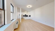 This contemporary 2-bedroom, 1-bathroom residence at 540 Bond Street in Bridgeport, CT offers a clean, modern aesthetic throughout. Light hardwood flooring runs continuously across the entire unit, creating a cohesive and airy feel. The open-concept living and kitchen area serves as the heart of the home, anchored by a structural column that adds an architectural touch. Large windows invite generous natural light and provide views of the surrounding neighborhood.

The kitchen is well-appointed with white shaker cabinetry featuring gold hardware, dark granite countertops, a matching dark tile backsplash, and a full suite of stainless steel appliances including a refrigerator, range, and over-the-range microwave. A peninsula island provides additional prep space and casual seating.

Both bedrooms are bright and well-proportioned, finished in crisp white walls with the same light hardwood flooring. The primary bedroom is notably spacious and benefits from an abundance of closet space, with multiple built-in closets featuring sleek black hardware. Four closets are distributed throughout the unit, offering excellent storage.

The bathroom is finished with speckled tile flooring, a full soaking tub with shower, and matte black fixtures, maintaining the home's modern, high-contrast design palette throughout.