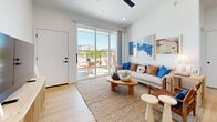 Located at 450 N Apache Rd in Buckeye, Arizona, this modern single-story home offers two bedrooms and two bathrooms within a thoughtfully designed floor plan. Light wood-look flooring flows throughout, lending warmth and visual continuity to every room.

The open-concept kitchen and living area forms the heart of the home. The kitchen features sleek gray cabinetry extending to impressive heights, stainless steel appliances, a white tile backsplash, and a central island with a butcher-block top that doubles as a dining space. The adjacent living room is bright and airy, with a ceiling fan overhead and large sliding glass doors that open directly to an outdoor patio, filling the space with natural light and Arizona views.

The primary bedroom is a comfortable retreat with dual windows, a ceiling fan, and a dedicated closet with en-suite bathroom access. The second bedroom also features a sliding glass door to the outdoors, providing its own private connection to the exterior. Both bedrooms share a calm, neutral aesthetic with warm accents.

The two bathrooms are clean and contemporary, each featuring white cabinetry with matte black hardware, large vanity mirrors, and light wood flooring. One bathroom includes a soaking tub with tiled surround. A hallway and two closets complete the well-organized layout of this efficiently designed home.