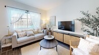 Located at 2501 Pico Blvd in Santa Monica, CA, this efficiently designed one-bedroom, one-bathroom unit offers a thoughtfully arranged floor plan that maximizes every square foot. The open-concept main living area seamlessly integrates the living room, dining space, and kitchen, creating a cohesive and functional layout. The living room features warm wood-tone flooring, a wall-mounted split A/C unit, and a large window with sheer curtains that invite natural light and offer views of the outdoor surroundings. The kitchen is outfitted with stainless steel appliances including a gas range, over-the-range microwave, and refrigerator, complemented by crisp white cabinetry, black hardware accents, and a classic subway tile backsplash. The bedroom is a tranquil retreat, featuring a mirrored sliding-door closet that enhances the sense of space, neutral tones, and natural light filtered through curtained windows. The bathroom showcases large-format marble-look wall tiles surrounding the tub-shower combination, a modern wall-mounted vanity, and a decorative gold-framed mirror, lending an elevated, spa-like feel. Throughout the unit, wood-look flooring ties the spaces together with a cohesive, contemporary aesthetic.