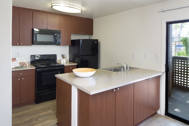 Classic Package II kitchen with black appliances, dark cherry cabinetry, beige laminate countertops, and hard surface flooring - eaves South Coast