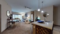 Located in Beavercreek, Ohio, this single-floor residence offers a thoughtfully designed open-concept layout that seamlessly connects the kitchen, dining, and living areas. The kitchen is a functional centerpiece, showcasing dark espresso cabinetry, black appliances, a granite-topped island with bar seating, pendant lighting, and track lighting overhead — all set on large-format tile flooring. The open living and dining space transitions to plush carpeting, creating a comfortable and inviting atmosphere. The living room is bright and airy, highlighted by a sliding glass door that opens to a private balcony with outdoor views, allowing natural light to fill the space. Two generously sized bedrooms feature carpet flooring, ceiling fans, and multiple windows dressed with horizontal blinds for light control. Each bedroom includes walk-in closet space with built-in shelving and hanging rods. The bathrooms are appointed with large-format tile floors, dark vanity cabinetry, white countertops, and well-lit mirrors. A dedicated laundry area and additional storage add practical convenience. Throughout the residence, neutral warm tones, panel-style interior doors, and consistent finishes contribute to a cohesive and modern aesthetic.