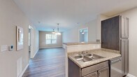 Located at 6306 Old Mooretown Rd in Williamsburg, VA, this single-floor residence offers a functional and well-appointed 2-bedroom, 2-bathroom layout. The open-concept living and dining area is anchored by durable hardwood-style flooring and a ceiling fan with pendant lighting, creating a bright and airy atmosphere. Natural light filters in through a large front-facing window, enhancing the clean, neutral color palette throughout.

The kitchen features dark espresso cabinetry, granite-style countertops, stainless steel appliances including a side-by-side refrigerator and electric range, a double-basin sink, and a breakfast bar peninsula that seamlessly connects to the living area. Recessed lighting adds a polished touch to the cooking space.

Both bedrooms are comfortably sized, each equipped with a ceiling fan and windows offering natural light. The primary bedroom is generously proportioned and finished with plush carpeting, while the second bedroom features the same hardwood-style flooring found in the main living areas. Each bedroom is supported by a dedicated closet for storage convenience.

The bathrooms are tastefully finished, with one featuring a modern floating vanity, granite-style countertop, and contemporary light fixture. A hallway connects the bedrooms to the shared living spaces, contributing to an efficient and cohesive floor plan throughout this Williamsburg home.