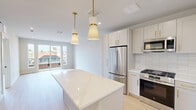 This thoughtfully designed one-bedroom, one-bathroom residence at 118 Elm St, Unit 306 in Westfield, NJ offers a well-appointed open layout finished with light hardwood flooring throughout. The kitchen is a standout feature, boasting sleek white cabinetry with brushed gold hardware, a classic subway tile backsplash, a quartz-topped center island with pendant lighting, and a full suite of stainless steel appliances including a gas range, built-in microwave, dishwasher, and French door refrigerator. The open living area flows seamlessly from the kitchen, bathed in natural light and offering a clean, minimalist aesthetic with crisp white walls and recessed lighting. The spacious primary bedroom features large windows and a sliding glass door that opens to a private balcony with views of the surrounding neighborhood, creating a bright and airy retreat. A dedicated closet provides practical storage. The bathroom is elegantly finished with large-format marble-look tile flooring, a frameless glass walk-in shower with marble tile surround, and a warm wood vanity topped with a white quartz counter. A hallway connects the rooms, completing this well-organized and stylishly modern residence in the heart of Westfield.