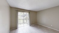 This single-floor unit offers a practical and functional layout across three bedrooms and two bathrooms. The combined kitchen and living area serves as the central hub of the space. The living room features light-toned tile flooring, neutral beige walls, and a textured ceiling, with a sliding glass door fitted with vertical blinds that opens to a balcony, allowing natural light to fill the room and providing outdoor views.

The galley-style kitchen runs parallel, featuring gray cabinetry, white countertops, a stainless steel sink, an electric range, and a full-size refrigerator. Appliances and cabinetry are efficiently arranged along both walls, maximizing functionality within the compact footprint.

A central hallway connects the bedrooms and bathrooms, with two closets providing additional storage. The bedrooms share the same light tile flooring and neutral wall tones as the main living areas, maintaining a consistent aesthetic throughout. The primary bedroom offers a comfortable amount of space relative to the overall floor plan.

Both bathrooms are equipped with full tub-shower combinations featuring built-in shelving, chrome fixtures, and white surrounds, complemented by neutral textured walls and clean, simple finishes.