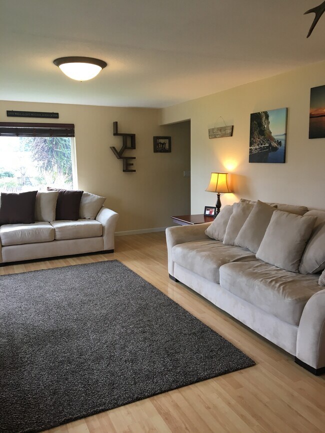 Large living room with lots of windows, wood burning fireplace. Light wood laminate floors. - 421 N 6th Ave SW