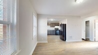 This single-floor residence in Louisville, Kentucky offers a clean, functional layout with thoughtful updates throughout. The living area is bright and open, benefiting from multiple windows that allow generous natural light to fill the space. Durable hardwood-style flooring runs throughout the main living and bedroom areas, providing a warm, cohesive look.

The kitchen is well-equipped and connects seamlessly to the living space through an open passthrough. It features dark gray shaker-style cabinetry, light granite-look countertops, and black appliances including a gas range with overhead ventilation, a dishwasher, and a full-size refrigerator. A double-basin sink sits beneath a window, adding both practicality and additional natural light to the cooking area. A dedicated closet space adjacent to the kitchen provides convenient storage.

The bedroom offers a calm, neutral palette with hardwood flooring, a built-in closet, and an electrical panel neatly integrated into the wall. The bathroom is clean and classic, featuring white square tile with a navy blue accent border, a shower-tub combination, a pedestal sink, and a frosted window for privacy and ventilation.

Throughout the space, neutral gray walls, white trim, and consistent flooring create a cohesive and move-in-ready environment suited for comfortable everyday living.