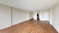 This 2-bedroom, 2-bathroom residence is thoughtfully laid out across a single floor, offering a comfortable and functional living environment. The spacious living area features warm wood-style flooring, neutral-toned walls, and a textured ceiling, creating a clean and inviting atmosphere. Floor-to-ceiling vertical blinds frame large sliding glass doors that fill the space with natural light and provide access to a private balcony with lush outdoor views.

Both bedrooms are generously sized, featuring plush carpeting and their own large windows with vertical blinds that open to outdoor scenery, allowing for abundant natural light throughout the day.

The galley-style kitchen is efficiently designed with ample cream-toned cabinetry on both sides, a stainless steel sink, a black refrigerator, an electric range, and a bright overhead light panel that keeps the workspace well-lit.

The two bathrooms are well-appointed. One features a dual-sink vanity with a full-width mirror and track lighting, complemented by open shelving for added storage. The second bathroom includes a single-sink vanity and a standalone glass-enclosed shower with tile surround. Both bathrooms maintain a light, neutral palette throughout.