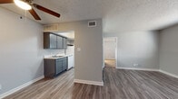 This single-story unit features a practical, well-organized layout with a neutral gray color palette and crisp white trim throughout. The living area is spacious and open, finished with wood-look plank flooring that extends through the main living spaces, and a ceiling fan overhead adds both comfort and style. Natural light enters through a window fitted with horizontal blinds, creating a bright and welcoming atmosphere. A pass-through counter connects the living area to the kitchen, enhancing the sense of openness between the two spaces.

The galley-style kitchen is efficiently designed, offering gray cabinetry, marble-look countertops, and white appliances including a refrigerator, electric range, and dishwasher. An under-cabinet range hood and built-in ventilation ensure proper airflow. The kitchen provides ample cabinet storage and counter workspace within its compact footprint.

The bedroom is carpeted for added comfort and receives natural light through a window with blinds. The bathroom includes a full-size soaking tub and shower combination with a curtain, a toilet, and wood-look flooring consistent with the rest of the unit. A textured ceiling is present throughout, adding a consistent architectural finish to the space.