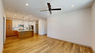 Located in Lady Lake, FL, this well-appointed 2-bedroom, 2-bathroom single-floor residence offers a thoughtfully designed open-concept layout. The living area features warm wood-look flooring, recessed lighting, and a ceiling fan, creating a bright and airy atmosphere with natural light streaming through large windows. The space flows seamlessly into the kitchen, which serves as a true centerpiece — showcasing a large waterfall-edge quartz island with an undermount sink, a two-tone cabinetry scheme pairing white uppers with warm wood lowers, subway tile backsplash, stainless steel appliances, and striking lantern pendant lights overhead. Both bedrooms are carpeted and generously proportioned, offering comfortable retreats. The primary bathroom impresses with a glass-enclosed walk-in shower clad in white subway tile, warm wood vanity cabinetry, white quartz countertop, and an illuminated mirror. The second bathroom features matching wood cabinetry and a tiled tub-shower combination. Additional highlights include three closets, a dedicated laundry area, a utility room, and a private balcony. The consistent use of wood-tone finishes and clean white walls throughout lends the home a cohesive, modern aesthetic.