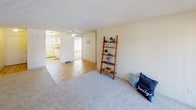 This single-floor residence offers a practical and comfortable layout designed to maximize livable space. The open living area is finished with plush carpeting and flows seamlessly into an adjoining space with light hardwood-style flooring, creating a natural transition between the relaxing and functional zones of the home. A ceiling fan overhead adds to the comfort of the main living area, which also benefits from a sliding door that invites natural light and outdoor access.

The kitchen is efficiently designed with light wood cabinetry extending to the ceiling for generous storage, a countertop with double sink, a full suite of white appliances including a refrigerator, dishwasher, and electric range, and a window that keeps the space bright and airy. Baseboard heating is present throughout.

The bedrooms are well-proportioned, featuring soft carpeting, textured ceilings, and windows fitted with vertical blinds that allow for adjustable natural light. Each room offers a calm, neutral palette ideal for personalization.

The bathroom is well-appointed with an extended vanity countertop, dual-sink setup, broad wall mirror with overhead lighting, and a tub-shower combination. Wood-style flooring in the bathroom adds a cohesive touch. A closet is conveniently accessible directly from the bathroom area, adding practical storage to the space.