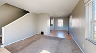 Located at 2100 Rhomberg Ave in Dubuque, Iowa, this two-story home offers a practical and functional layout across two floors. The main level combines the living room and kitchen into a cohesive, open flow. The living room features neutral gray walls, plush carpet, and multiple windows that invite abundant natural light and neighborhood views. It transitions seamlessly into the kitchen area, which is finished with warm oak cabinetry, dark granite-style countertops, a white tile backsplash, and light hardwood flooring. White appliances, including a full-size refrigerator and range, are included. A staircase leads to the upper floor, where both bedrooms are found. The primary bedroom is generously sized, featuring soft carpet, dual windows with exterior views, and a ceiling fan with light fixture. It includes two closets with clean white panel doors. The second bedroom also offers carpet, dual corner windows, and a ceiling fan, filling the room with bright, natural light. The full bathroom is appointed with a combination tub and shower unit, a window for ventilation, and clean white fixtures. A hallway connects the upstairs rooms efficiently. Throughout the home, neutral tones and consistent finishes create a calm, understated atmosphere.
