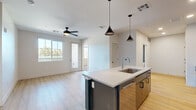 Located at 151 W High Country Trail in Flagstaff, AZ, this contemporary 2-bedroom, 2-bathroom residence offers a thoughtfully designed single-floor layout with modern finishes throughout. The open-concept kitchen and living area serves as the heart of the home, anchored by a striking kitchen island with a bold teal base, white quartz countertops, and a stainless steel sink. The kitchen features two-tone cabinetry — dark grey lowers paired with warm wood uppers — complemented by a classic white subway tile backsplash and a full suite of stainless steel appliances, including a gas range and French door refrigerator. Pendant lighting adds a sleek, modern touch above the island. Light-toned hardwood-style flooring runs throughout the main living areas, while the living room benefits from natural light through large windows and direct access to an outdoor space via a glass door. A ceiling fan keeps the space comfortable. The bedrooms are carpeted and well-lit, each with a ceiling fan and windows framing views of the surrounding landscape. The two bathrooms are finished with warm wood vanities, dual sinks, white quartz countertops, and bold teal accent walls that add a distinctive design element. The hallway connects the rooms efficiently, and a dedicated closet provides added storage.