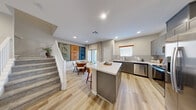 Located at 7567 Jumping Cholla Ct in Las Vegas, NV, this well-appointed two-story home offers 2 bedrooms, 3 bathrooms, a dedicated office, and two closets across two thoughtfully designed floors. The main level features an open-concept layout that seamlessly connects the kitchen, dining room, and living area. The kitchen is outfitted with gray shaker-style cabinetry, white quartz countertops, a central island with bar seating, subway tile backsplash, and a full suite of stainless steel appliances including a range, microwave, dishwasher, and refrigerator. Light wood-look flooring flows throughout the main level, while the dining area is accented by a striking triptych wall art display adjacent to the carpeted staircase. Upstairs, the more expansive floor houses the bedrooms, living room, and office. The second living room offers plush carpet and natural light, while the office features a ceiling fan and window. The bedrooms include ceiling fans and closets, with the primary bedroom offering a generous walk-in closet with built-in shelving. The three bathrooms are finished with gray vanities, quartz countertops, and wood-look tile flooring. Neutral tones and recessed lighting throughout give the home a clean, contemporary ambiance.
