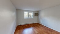 Located at 567 Sagamore Ave in Portsmouth, NH, this 2-bedroom, 1-bathroom residence offers a practical and well-maintained single-floor layout. The space is finished with warm hardwood-style flooring throughout the main living areas and bedrooms, complemented by neutral white walls that create a bright, clean aesthetic. The primary bedroom is a comfortable size, featuring a grid-pane window that allows natural light to filter in alongside a baseboard heating system and a wall-mounted AC unit for year-round climate control. The second bedroom offers a similarly light-filled environment with its own window and hardwood-style floors. The kitchen stands out as a functional highlight, equipped with white shaker-style cabinetry, dark granite countertops, a white subway tile backsplash, and stainless steel appliances including a range, microwave, and dishwasher. Tile flooring and a ceiling fan complete the kitchen's practical design. The bathroom is finished in classic white, featuring black-and-white mosaic tile flooring, a full tub and shower with white tile surround, and a white vanity. A dedicated closet provides additional storage, rounding out this efficient and well-appointed Portsmouth residence.