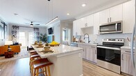 This well-appointed 2-bedroom, 3-bathroom residence in Johnstown, Colorado offers a thoughtfully designed single-floor layout with modern finishes throughout. The open-concept kitchen serves as a central hub, featuring granite countertops, a large island with pendant lighting, two-tone cabinetry with matte black hardware, a subway tile backsplash, and stainless steel appliances including a range and over-the-range microwave. The kitchen flows seamlessly into the living room, which is bright and inviting with crown molding, a ceiling fan, and French doors that open to an outdoor balcony. The primary bedroom is a comfortable retreat with large windows, a ceiling fan, and direct access to both a walk-in closet with wire shelving and an en-suite bathroom. The primary bath features granite countertops, wood-toned cabinetry, a framed mirror, and matte black fixtures. The second bedroom also benefits from ample natural light, French doors, and a ceiling fan. A full bathroom with a soaking tub and tiled surround serves additional guests. Two dedicated closets provide generous storage throughout the unit. Luxury vinyl plank flooring runs through the main living areas, while plush carpet adds warmth to the bedrooms.