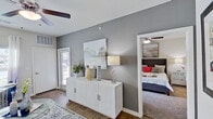 This single-floor residence offers a thoughtfully designed layout that balances comfort and modern style. The living area sets an inviting tone with warm hardwood-style flooring, a ceiling fan, and large windows that draw in natural light. A stylish credenza and curated wall art anchor the space, while an open sightline connects seamlessly to the rest of the unit.

The kitchen is outfitted with dark espresso cabinetry, light granite-style countertops, a subway tile backsplash, and black appliances including a range, dishwasher, and refrigerator. A double-basin sink sits at the center, making this a fully functional and attractive culinary space.

The bedroom offers a calm retreat with plush carpeted flooring, a ceiling fan, and a window with exterior views. The room is generously proportioned, easily accommodating a queen or king bed, and flows naturally from the main living area through a connecting hallway.

The bathroom features hardwood-style flooring, a tiled tub-shower combination with a curtain rod, a wall-mounted dark wood cabinet, and a granite-topped vanity — delivering a clean and functional design.

Throughout the unit, a neutral gray and white color palette, consistent ceiling fans, and cohesive finishes create a unified and contemporary aesthetic.