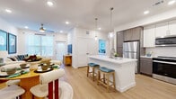 This well-designed one-bedroom, one-bathroom residence in Georgetown, Texas offers a thoughtfully planned open-concept layout that maximizes its comfortable footprint. Light-toned hardwood flooring flows throughout, unifying the spaces and enhancing the bright, airy atmosphere created by recessed lighting and natural light from multiple windows.

The kitchen is a standout feature, showcasing a two-tone cabinet design with white upper cabinets and warm taupe lower cabinets, complemented by white quartz countertops and a subway tile backsplash. A central island with an undermount sink and seating for two serves as both a functional workspace and casual dining area, illuminated by pendant globe lighting. Stainless steel appliances, including a refrigerator, range, microwave, and dishwasher, complete the space.

The open living area flows naturally from the kitchen, featuring a ceiling fan and access to natural light through windows with blinds. The spacious primary bedroom accommodates a full-sized bed, offers a generous window with outdoor views, and includes access to a private closet. The bathroom features a white vanity with quartz countertops, brushed nickel hardware, and a tub-shower combination with marble-style tile surround.