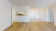 Located in Torrance, CA, this single-floor residence on Anza Avenue offers a clean, functional layout with a variety of thoughtfully appointed spaces. The living area greets visitors with light wood-tone flooring, a large window with vertical blinds that invites natural light, and a textured ceiling. A pass-through window connects the living space to the kitchen, creating an open, communicative feel between the two areas. The kitchen features white cabinetry, granite-look countertops, white appliances including a range and over-the-range microwave, and light tile flooring that extends throughout the functional areas of the home. The bedrooms are carpeted for comfort and each includes a ceiling fan with light fixture and windows with vertical blinds that allow for natural light and outdoor views. The bathrooms are finished with matching granite-look countertops, white vanity cabinetry, large mirrors, and light tile flooring. One bathroom includes a shower-tub combination with a window for natural ventilation. The overall design palette of white walls, neutral flooring, and consistent finishes throughout lends the space a cohesive, well-maintained appearance suited for comfortable everyday living in the South Bay area of Los Angeles.